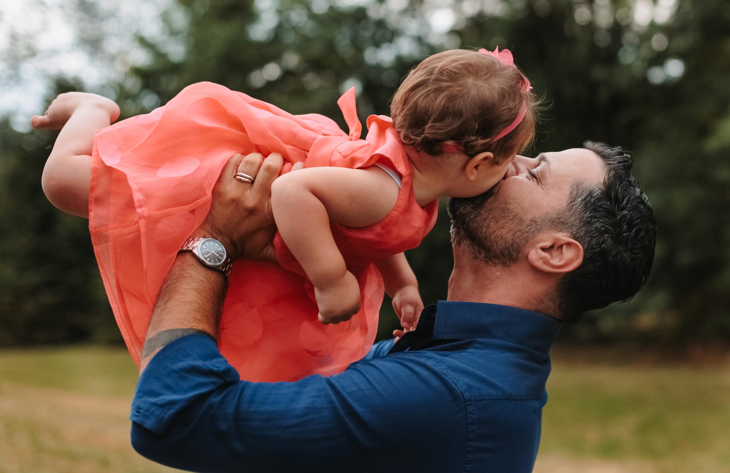 Papà che gioca con la sua bimba al parco in una giornata estiva, in un momento spontaneo e pieno di dolcezza.